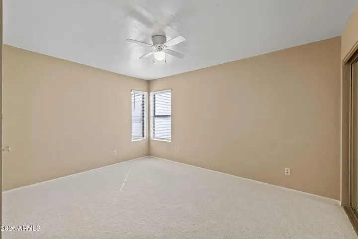 Primary bedroom with new carpet, ceiling fan, and neutral tones.
