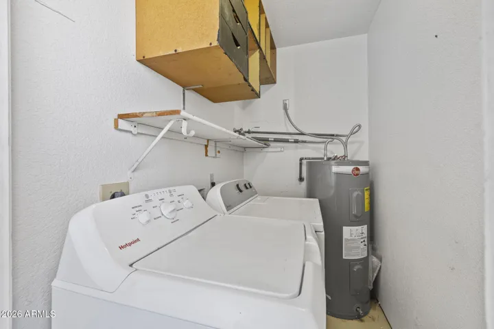 Dedicated laundry room with new washer, dryer, water heater, and storage.
