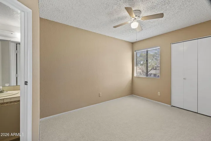 Spacious secondary bedroom with new carpet, ceiling fan, and natural light.