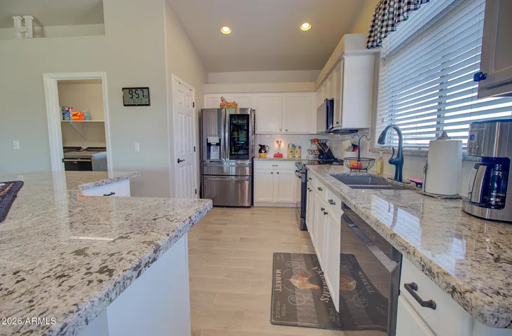 Thick granite counters, cabinets with hardware, plank tile floors, recessed lighting