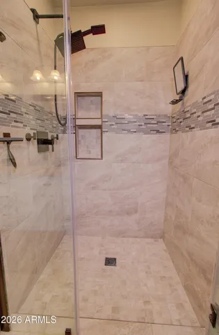 Shower in master is complete with niche, tile accents and glass door