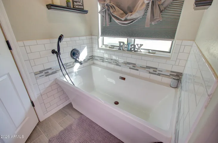 Spa like tub in master bath with tile surround, elevated fixtures and window