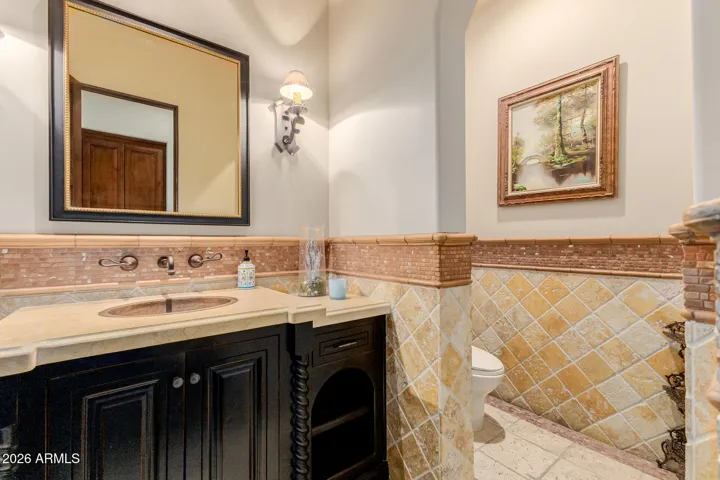 Powder Room with Upgraded Cabinets, Wall Mounted Sconce & Detailed Decorative Wall Tile Work.
