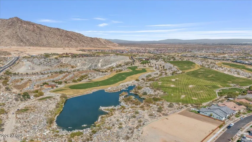 Aerial view of the nearby golf course featuring maintained fairways, open green space, and a scenic water feature within the surrounding Verrado community.
