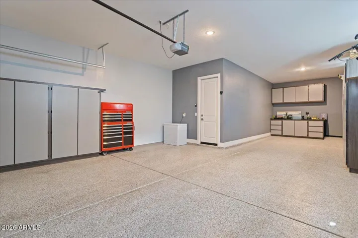 A spacious 3-car garage featuring epoxy floors, built-in cabinetry, and a dedicated workbench—designed for organization and functionality.
