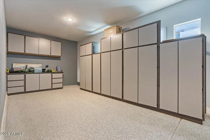 3-car epoxy garage featuring extensive built-in cabinetry, dedicated workbench space, and exceptional storage for tools, hobbies, and everyday organization.