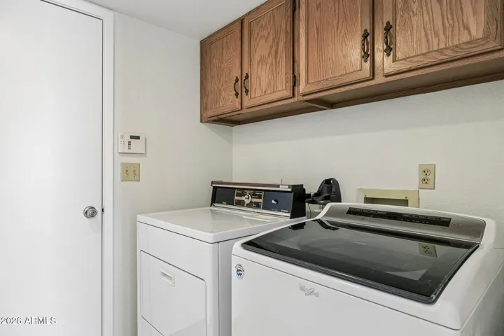 Utility room with storage closet (not shown) and upper cabinets, garage access