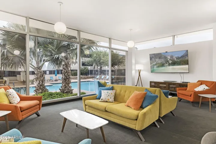 Mid-century inspired resident lounge with floor-to-ceiling windows overlooking the pool.