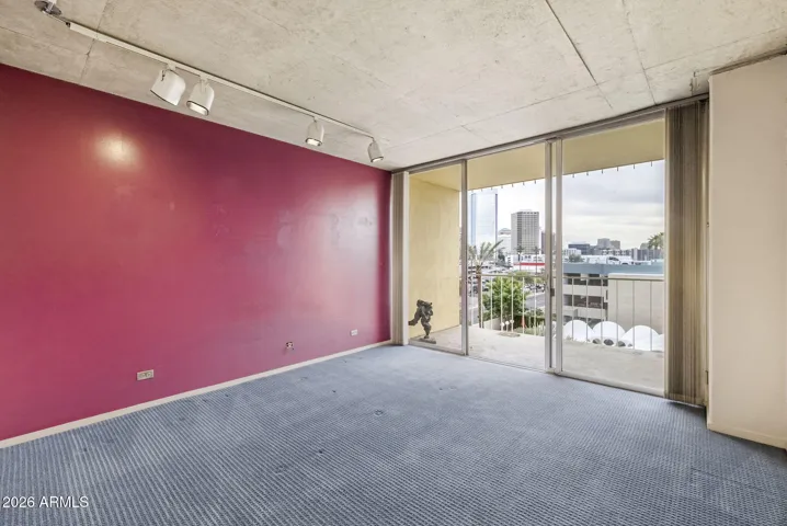 Light-filled bedroom with sliding glass doors opening to a private south-facing balcony, perfect for enjoying morning light and evening city views.
