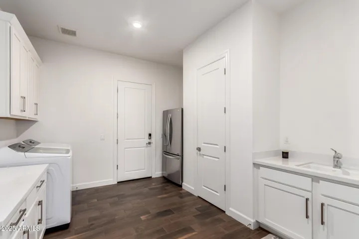 Spacious laundry room with extra cabinets, sink and counter space and 3 car garage door access