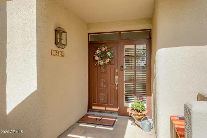 Covered front entry featuring solid wood door, decorative accents, and welcoming entryway.