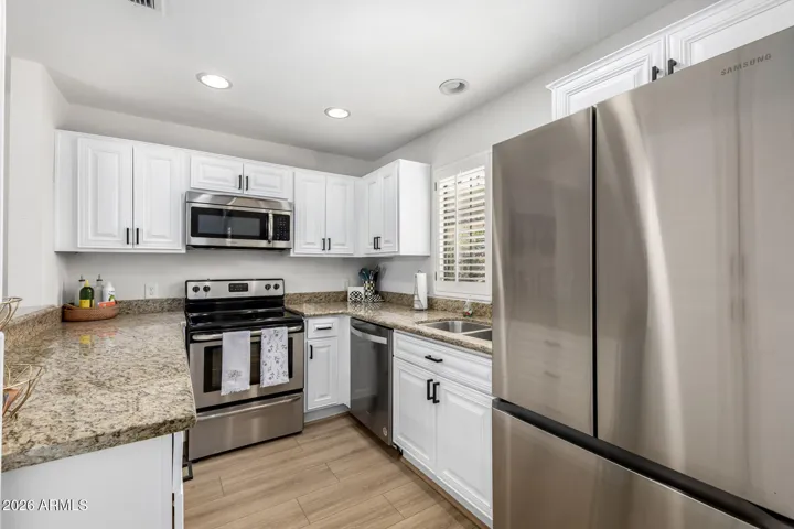 Functional kitchen layout featuring ample cabinet storage, granite counters, and recessed lighting.