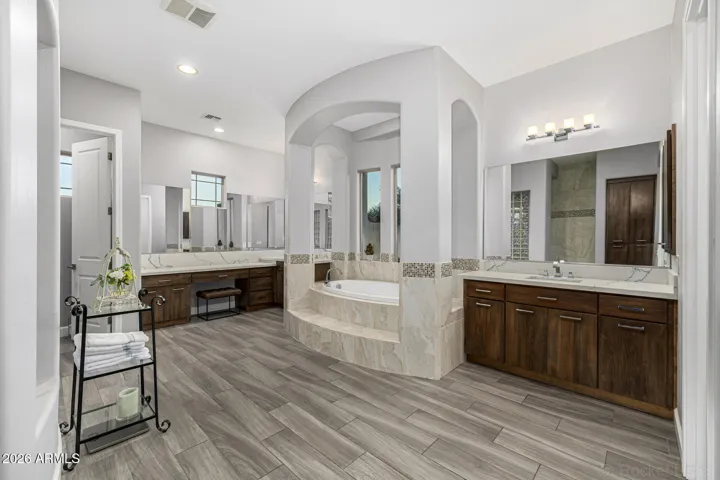 Large primary retreat with luxurious spa like bathroom featuring walk-in shower, soaking tub, dual sinks, separate vanity areas, granite counters, Restoration Hardware lighting and extended primary suite closet.