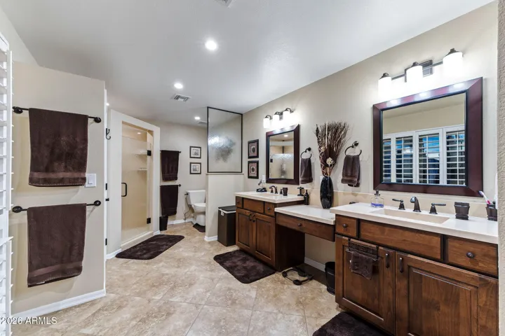 The expanded primary bathroom with double sinks, walk-in shower and private toilet area.