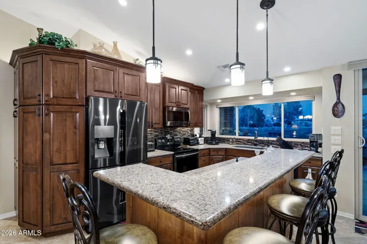 The gourmet kitchen is equipped w/built-in appliances, pantry cabinets, tile backsplash, granite counters and drop lighting.