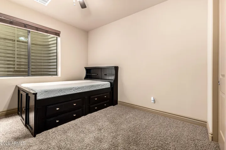 Functional bedroom featuring built-in storage bed, soft carpeting, and natural light. Located in Goodyear, this space maximizes storage while maintaining a clean, comfortable layout.