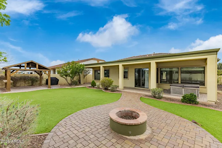 Spacious backyard retreat in Goodyear featuring covered patio, artificial turf, and spa area. Enjoy indoor-outdoor living with shaded seating and well-designed landscaping.