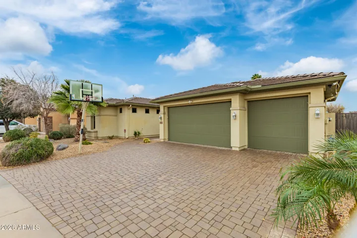 Large paver driveway leading to a 3-car garage, offering ample parking and durability. This Goodyear home combines functionality with upgraded exterior finishes for everyday convenience.
