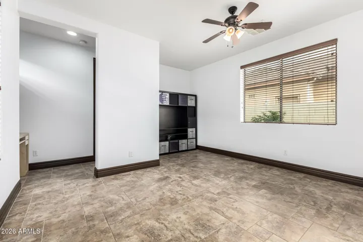 Bright open living space in this Goodyear home featuring durable tile flooring, neutral paint, and ceiling fan for comfort. Ideal for entertaining or relaxing, with easy flow toward adjacent rooms and updated finishes that enhance everyday living.
