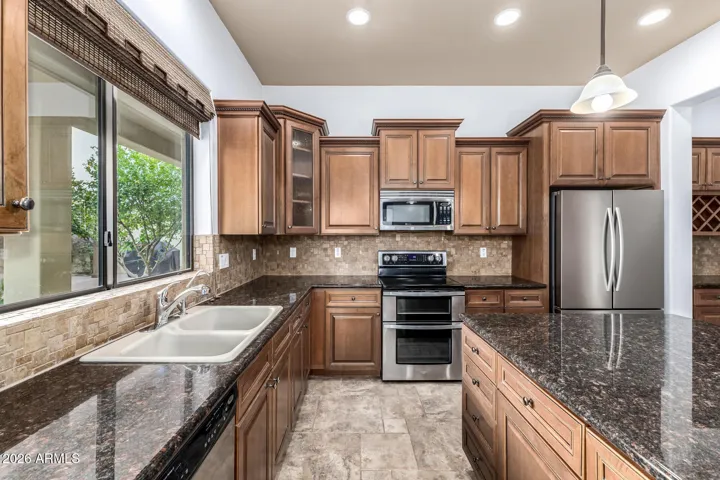 Upgraded kitchen with granite countertops, double oven range, and custom cabinets. Designed for both everyday living and entertaining in this desirable Goodyear home.