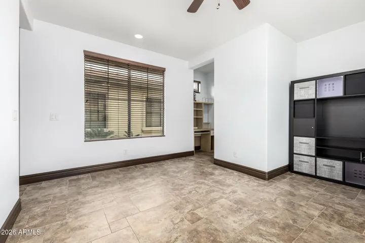 Versatile bonus room in Goodyear featuring tile flooring, natural light, and built-in workspace—perfect for a home office, gym, or additional living area.