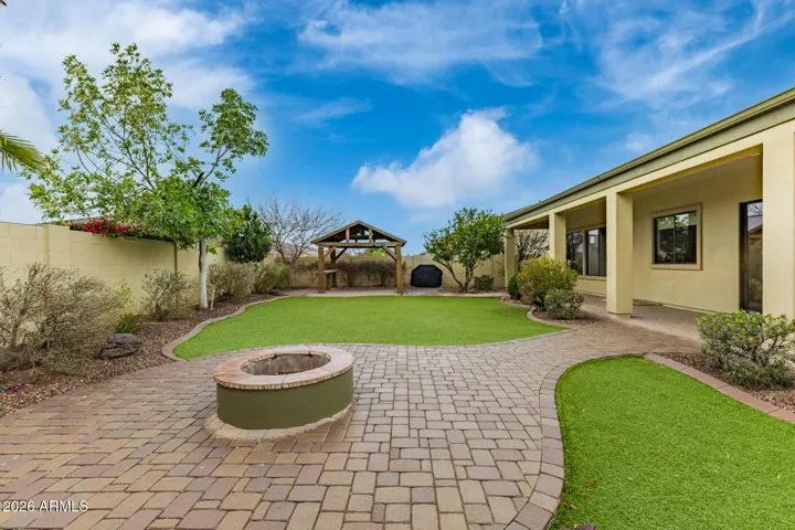 Inviting backyard in Goodyear with paver patio, built-in fire pit, and lush green turf. Perfect for outdoor entertaining with low-maintenance landscaping and open space for gatherings.