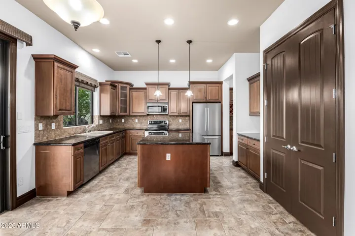 Beautiful kitchen with granite countertops, large center island, stainless steel appliances, and custom cabinetry. This Goodyear home offers a chef-inspired space perfect for cooking and entertaining.
