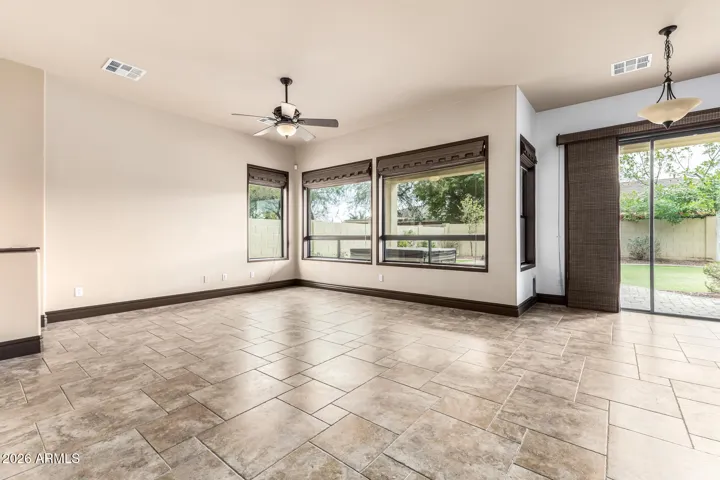 Bright and open living area with large windows, tile flooring, and backyard views. This Goodyear home offers seamless indoor-outdoor flow, perfect for entertaining or relaxing in a comfortable setting.