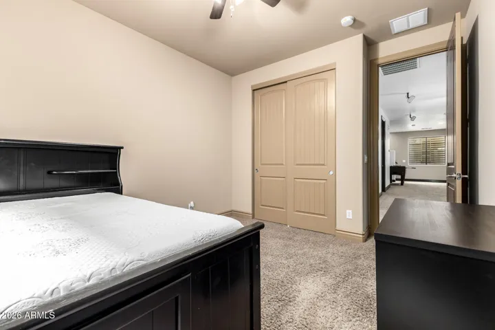 Well-sized bedroom with carpet flooring, large closet, and convenient access to adjacent living areas. Neutral tones and ceiling fan enhance comfort in this Goodyear home.