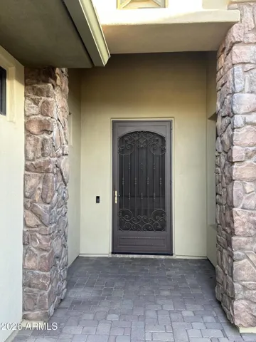 Stunning iron front door framed by stone columns and paver entryway. This upgraded feature adds security, style, and architectural detail to this Goodyear home’s grand entrance.