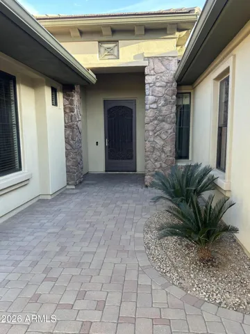 Elegant courtyard entry with paver flooring and stone accents creates a warm and private entrance. This inviting outdoor space enhances the home’s design and adds character to this Goodyear property.