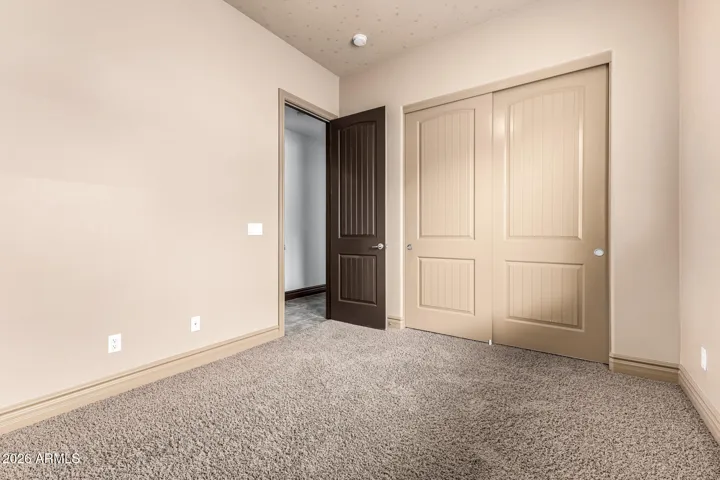 Well-appointed bedroom in Goodyear featuring soft carpeting, spacious closet, and neutral finishes—offering versatility and move-in ready comfort.