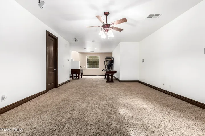 Spacious game and recreation area with plush carpet and ceiling fans for added comfort. This versatile Goodyear space offers room for entertainment, workouts, or additional living needs.