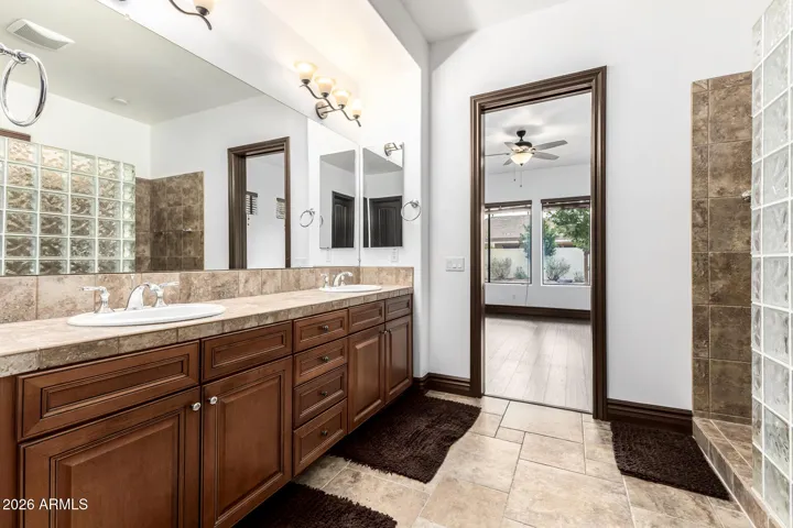 Expansive ensuite bathroom in Goodyear with dual vanities, large mirrors, updated lighting, and direct access to the bedroom—blending functionality with refined finishes.