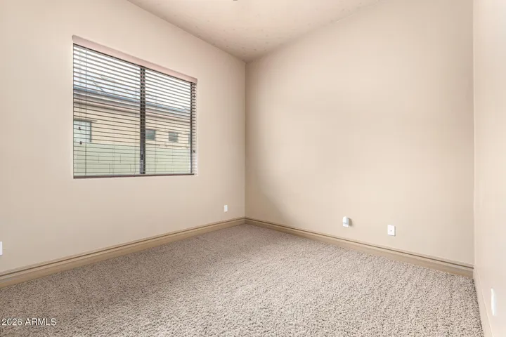 Comfortable secondary bedroom in Goodyear with plush carpeting, neutral tones, and natural light—perfect for guests, family, or a home office setup.