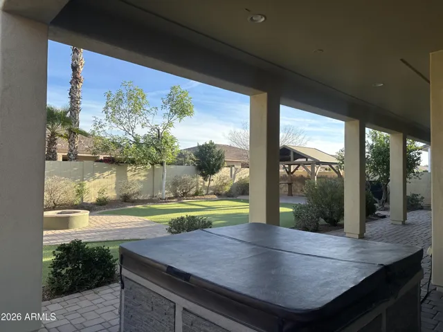 Covered patio in Goodyear overlooking landscaped yard, featuring spa and extended paver space. Perfect for year-round enjoyment and seamless outdoor living.