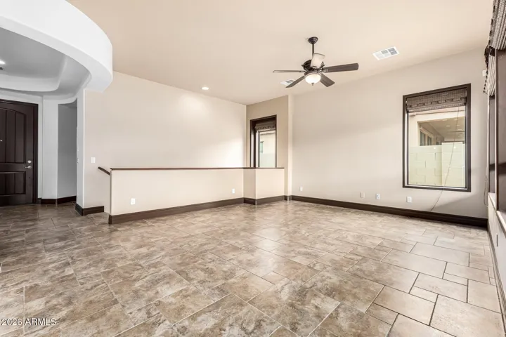 Expansive living room featuring tile flooring, ceiling fan, and neutral tones. This open-concept space in the Goodyear home provides flexibility for modern living and easy furniture arrangement