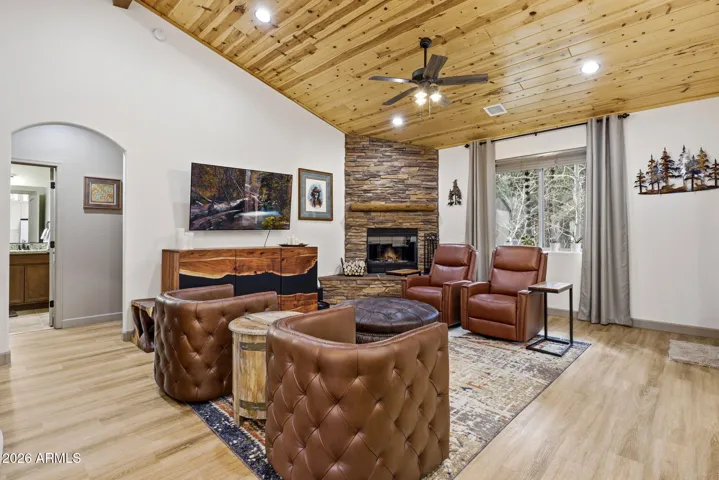 Modern ceiling fan in great room with stacked stone gas fireplace