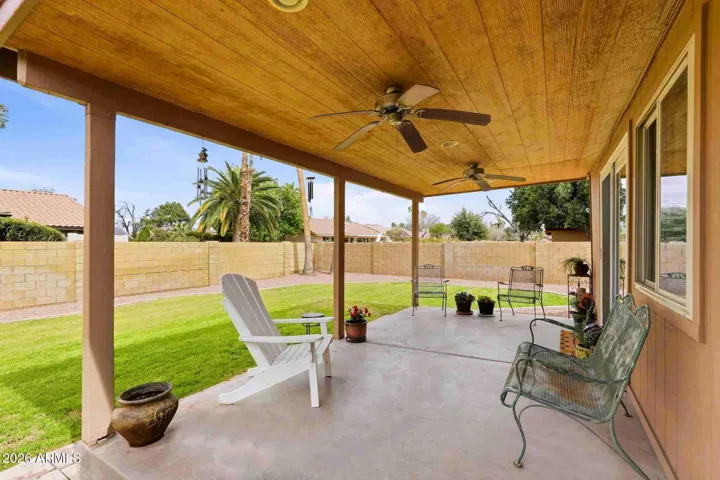 Covered patio with ceiling fans looks over lush lawn.