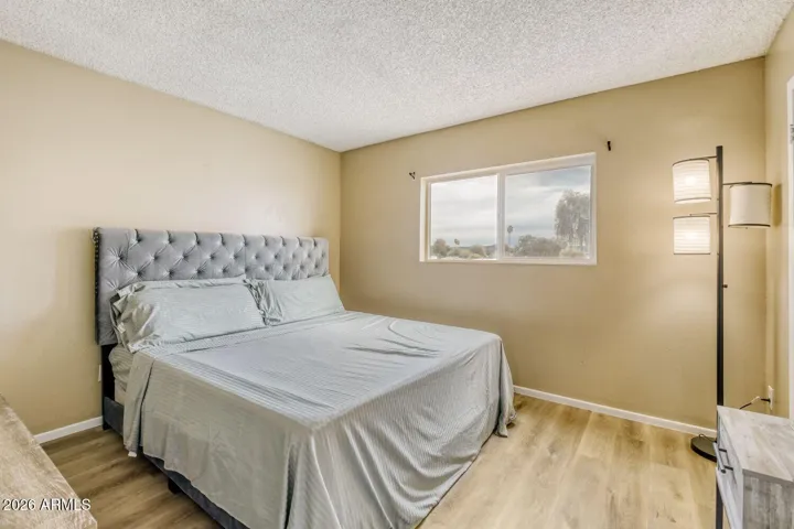 Bright primary bedroom with wide window and clean, open layout.