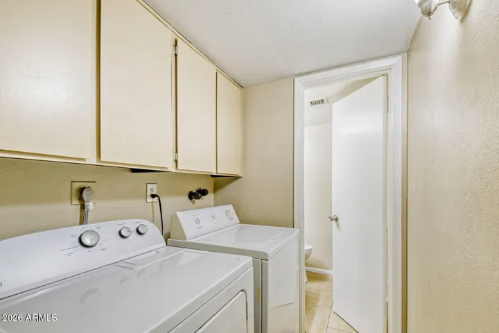 Main floor laundry room with washer and dryer included and overhead cabinets for storage.