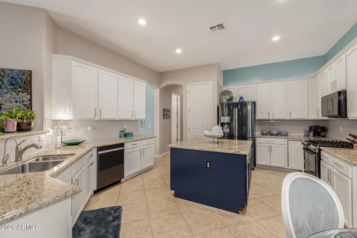 Painted white cabinets, navy island cabinets, custom paint, and tile blackspash really brighten and elevate the kitchen.