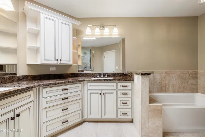 The primary bath has been upgraded with cream cabinets, marble counters, walk-in shower and a separate tub with tile surrounding.