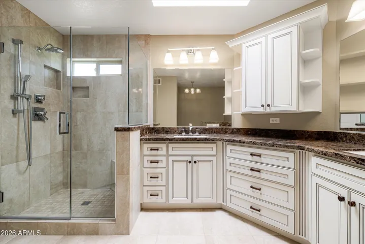 The walk-in shower has a glass door and porcelain tile to the ceiling.