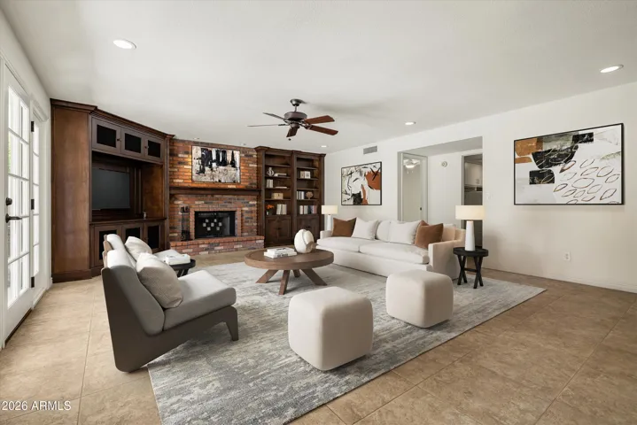 this cozy family room offers a wood burning fireplace, custom built-in entertainment center with shelving and french doors to the backyard.