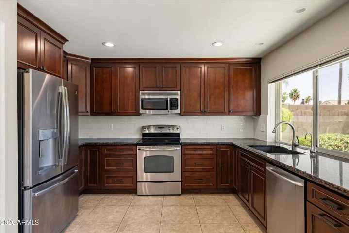 This kitchen offers GE Stainless appliances, granite counters, subway tile backsplash and cherry stained wood cabinetry.