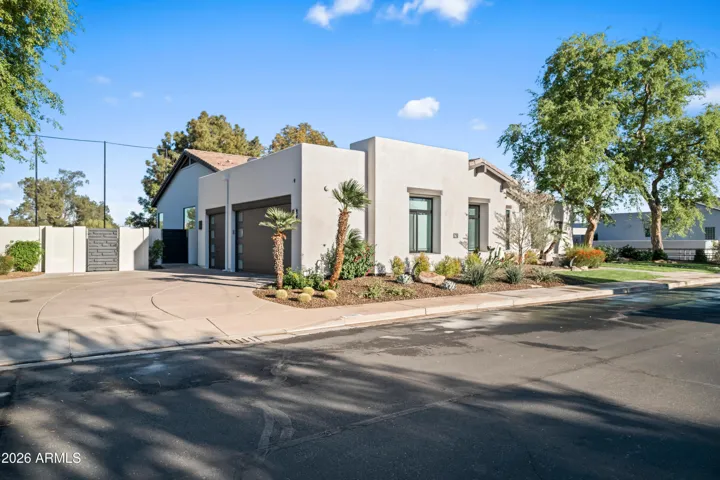 Welcoming front entry with stone walkway, desert landscaping, and mature trees. This Scottsdale home features updated outdoor design and a warm, inviting entrance.
