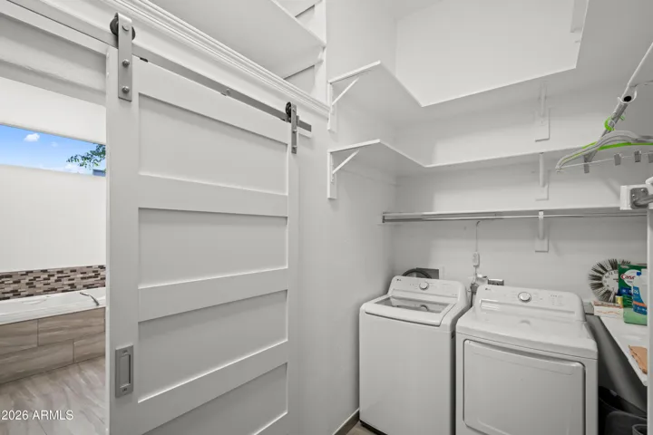 Functional Scottsdale laundry area combined with a second walk-in closet. Features storage shelving, washer and dryer, and efficient layout.
