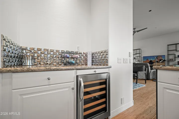 Stylish Scottsdale bar featuring built-in wine cooler, granite counters, and decorative backsplash. Perfect for entertaining and everyday convenience.