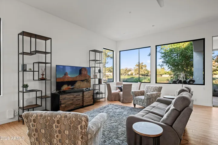 Spacious Scottsdale living room with large windows, wood flooring, and abundant natural light. Open layout offers seamless connection to outdoor spaces and scenic views.